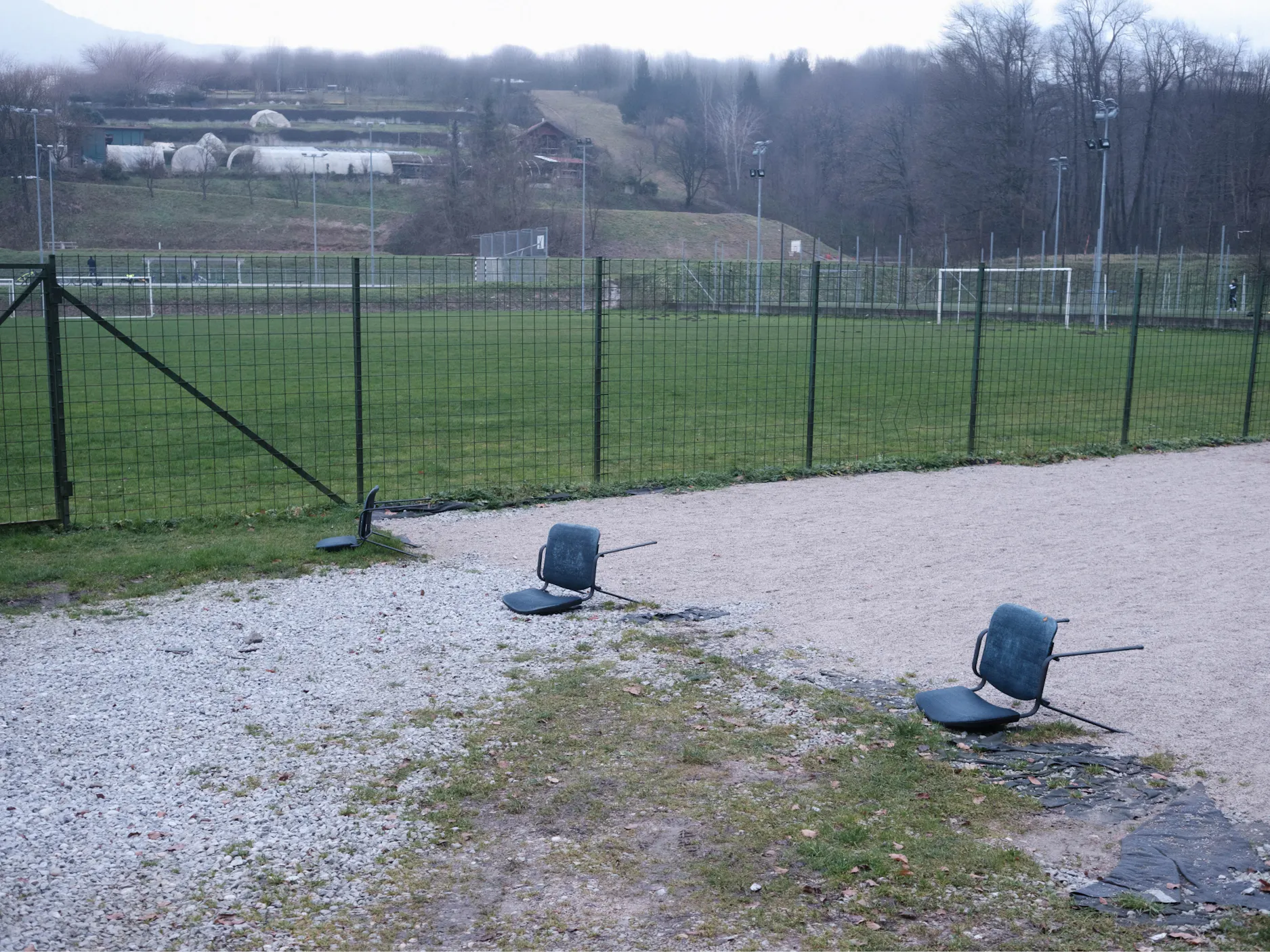 Trije prevrjeni stoli zraven nogometnega igrišča